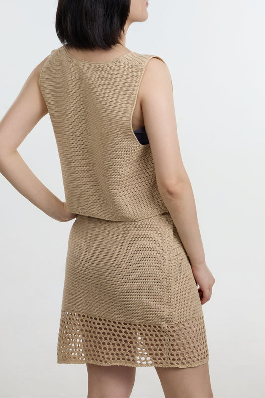 Woman wearing a beige sleeveless top and skirt set on a white background