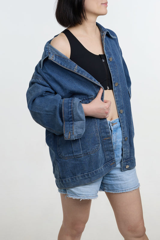Person wearing a denim jacket and shorts on a white background