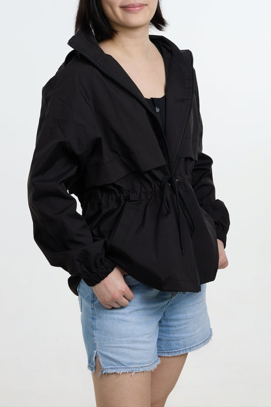 Person wearing a black jacket and denim shorts on a white background